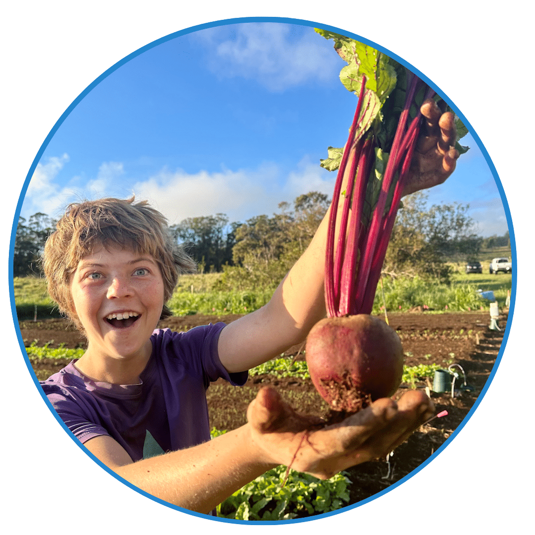 Entrepreneurship Agriculture: A person in a purple shirt smiles while holding a large beetroot in a garden with greenery and other plants in the background, embodying the hands-on spirit of entrepreneurship education.